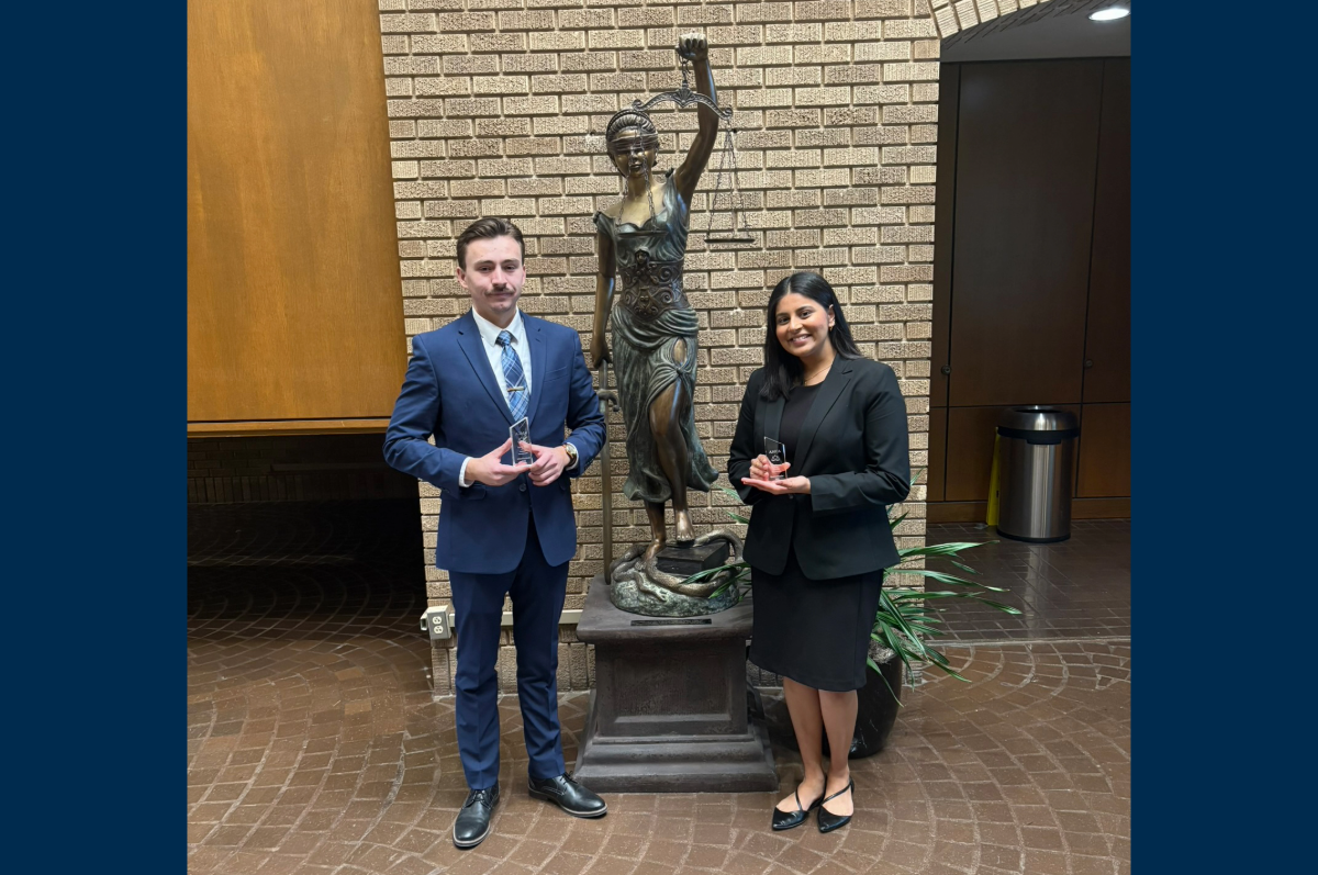 young man and young woman stand by statue with trophies